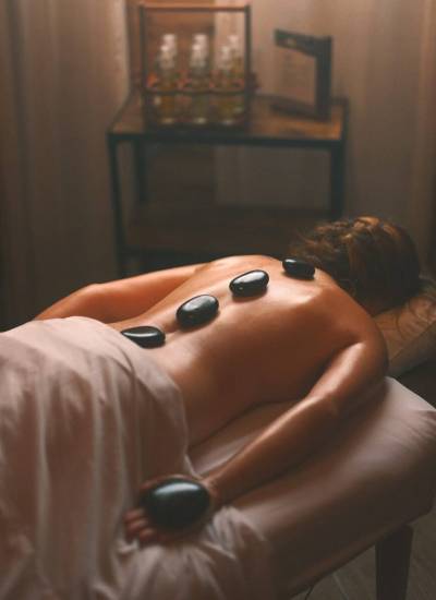 a woman laying on a bed with hot stones on her back